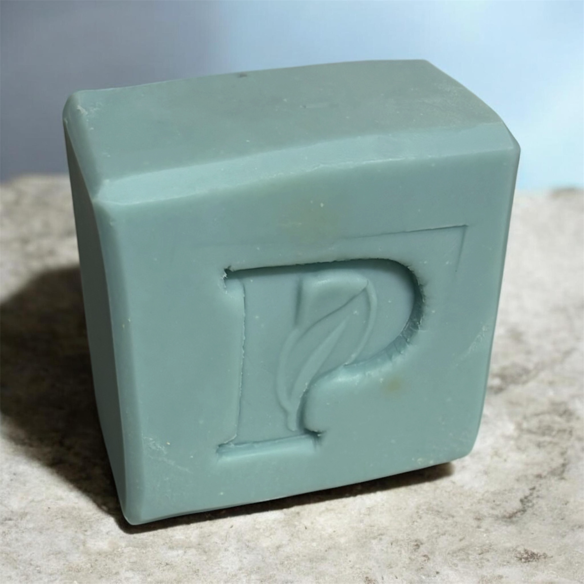 Prudent Preservations muted teal embossed bar soap with leaf emblem, natural ingredients, cube shape.
